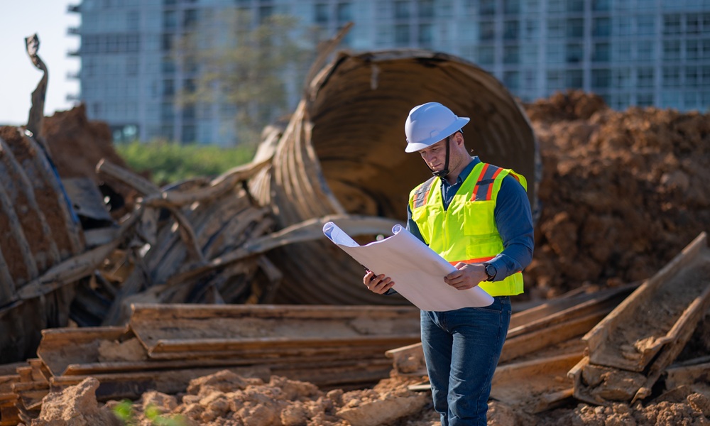 Engineer in a safety vest reviewing plans at a demolition and excavation site